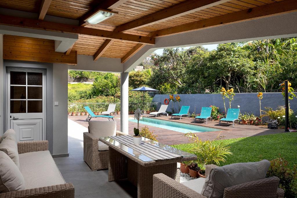a patio with a table and chairs and a pool at Paradise House Calheta in Calheta