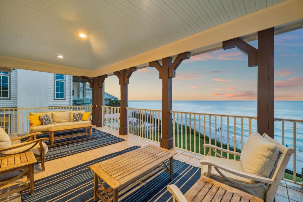a porch with chairs and tables and the ocean at Always On My Mind by 30A Escapes in Seacrest