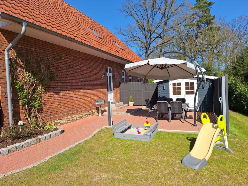 a backyard with an umbrella and a playground at Ferienwohnung Alte Schule in Lonnerbecke