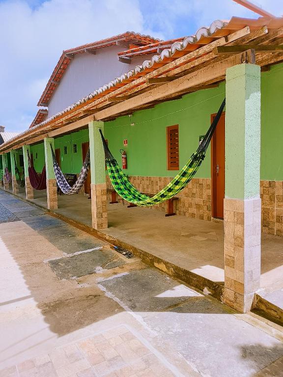 a green building with a hammock outside of it at Bom Viver Pousada ltda in Viçosa do Ceará