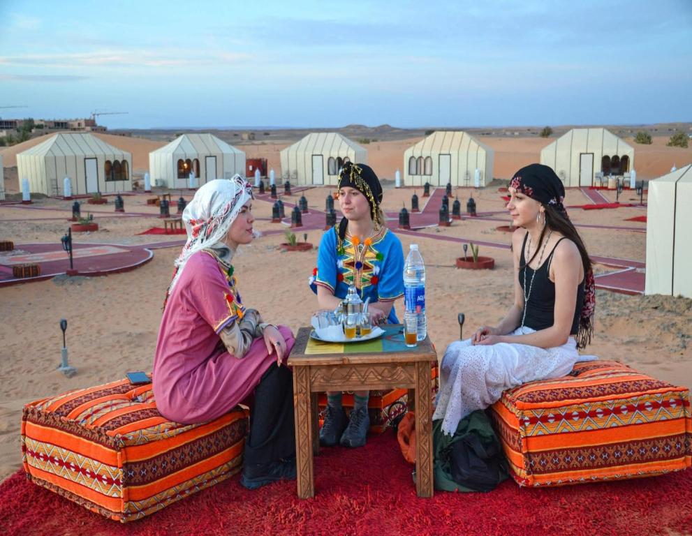 three women sitting around a table in the desert at Bivouac Camel Trips in Merzouga