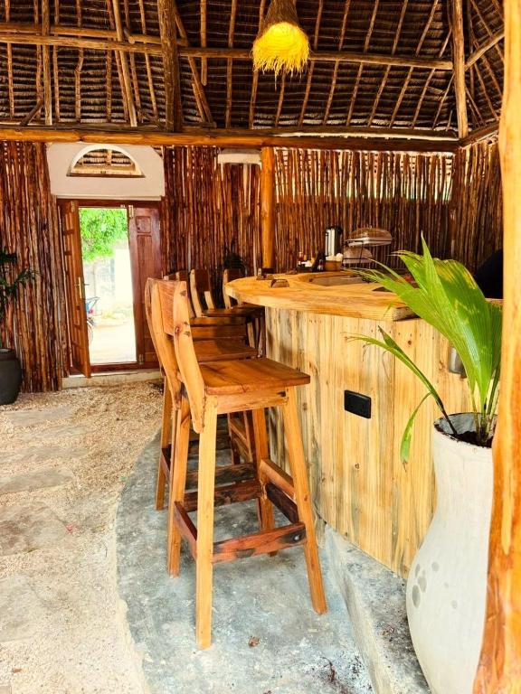 a bar in a resort with a table and chairs at Compass Hostel in Nungwi