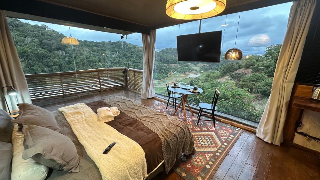 a bedroom with a bed and a large window with a table at Sunrise in Domingos Martins
