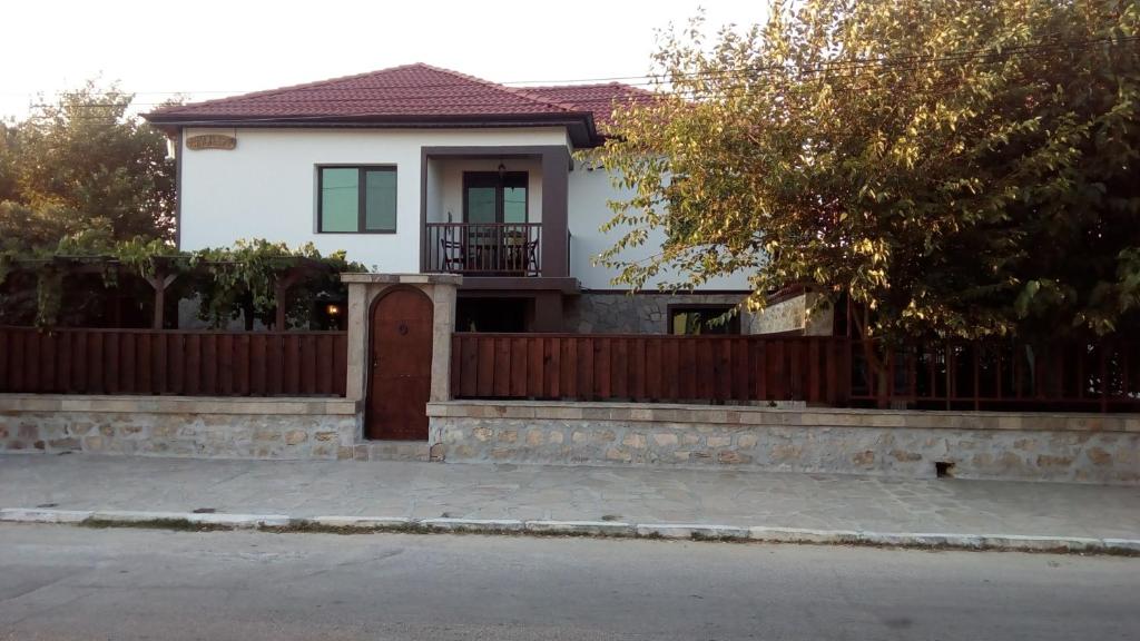 a white house with a fence and a gate at Guesthouse Orlovo in Orlovo