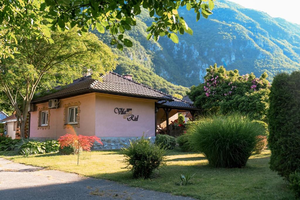 ein kleines Haus mit einem Berg im Hintergrund in der Unterkunft Vila RID in Perućac