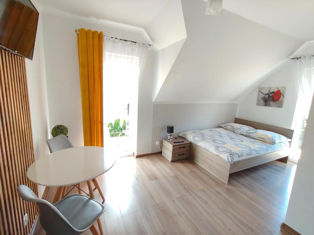 a bedroom with a bed and a table and a window at Noclegi Pod Lasem in Polańczyk