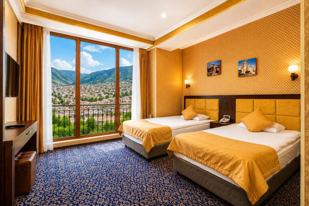 a hotel room with two beds and a large window at Ruma Qala Hotel in Sheki