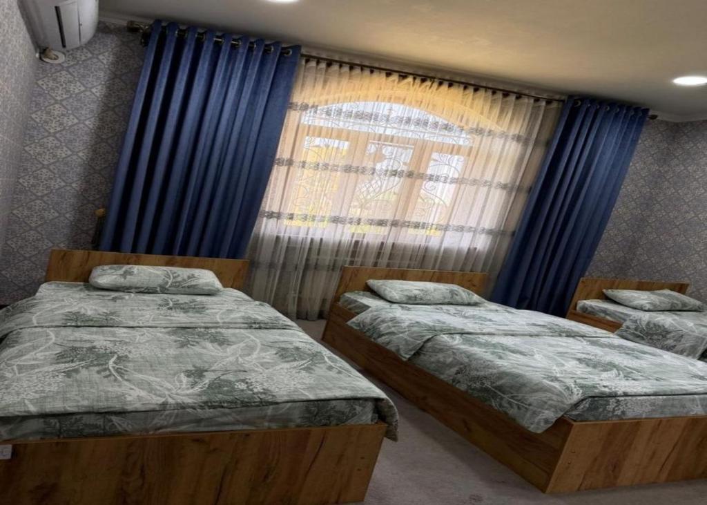 a bedroom with two beds and a window with blue curtains at Marshall in Termiz