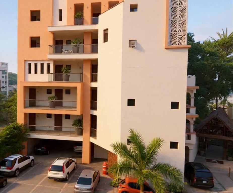 a building with cars parked in a parking lot at Villas & Suites Santa Monica in Rincon de Guayabitos