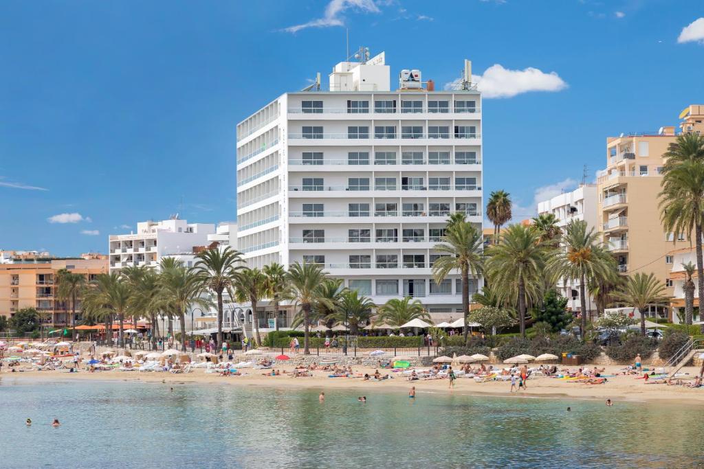 uma praia em frente a um grande edifício branco em Hotel Ibiza Playa em Ibiza
