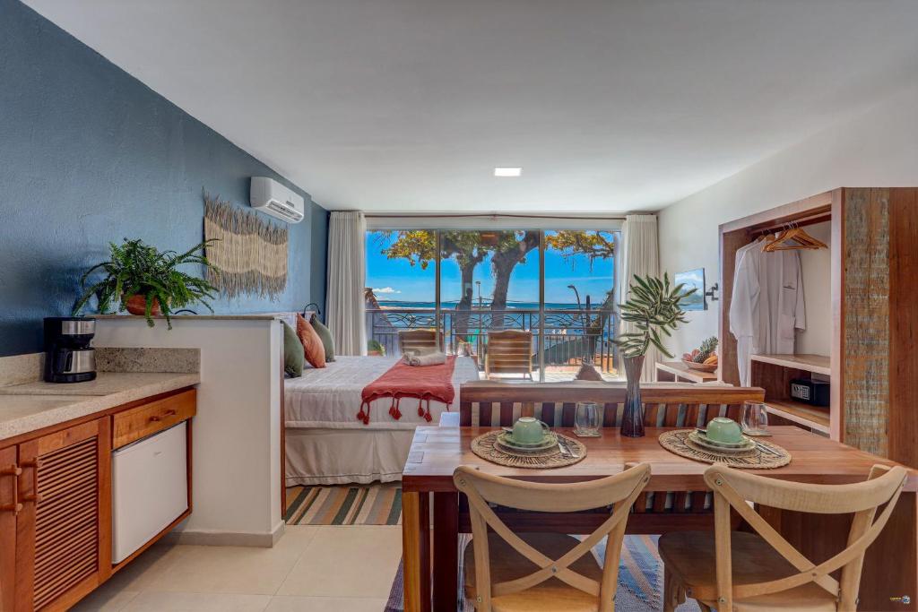 a kitchen and living room with a table and a bedroom at Cairé Suites in Itacaré