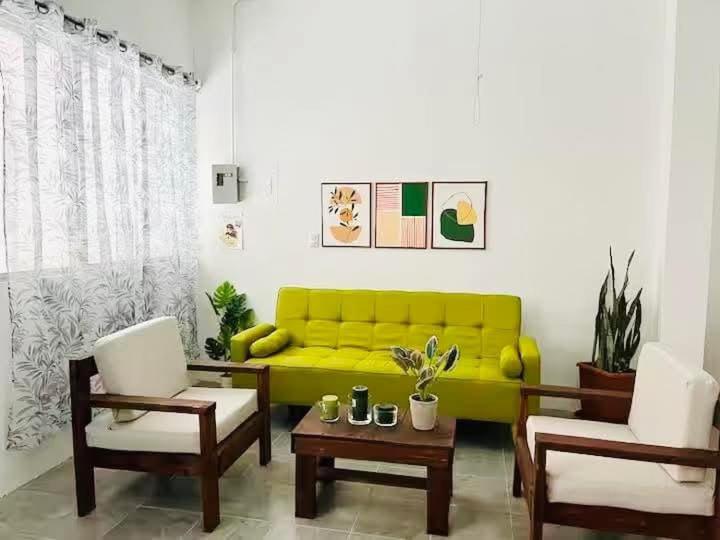 a living room with a yellow couch and two chairs at Lu House in Flores