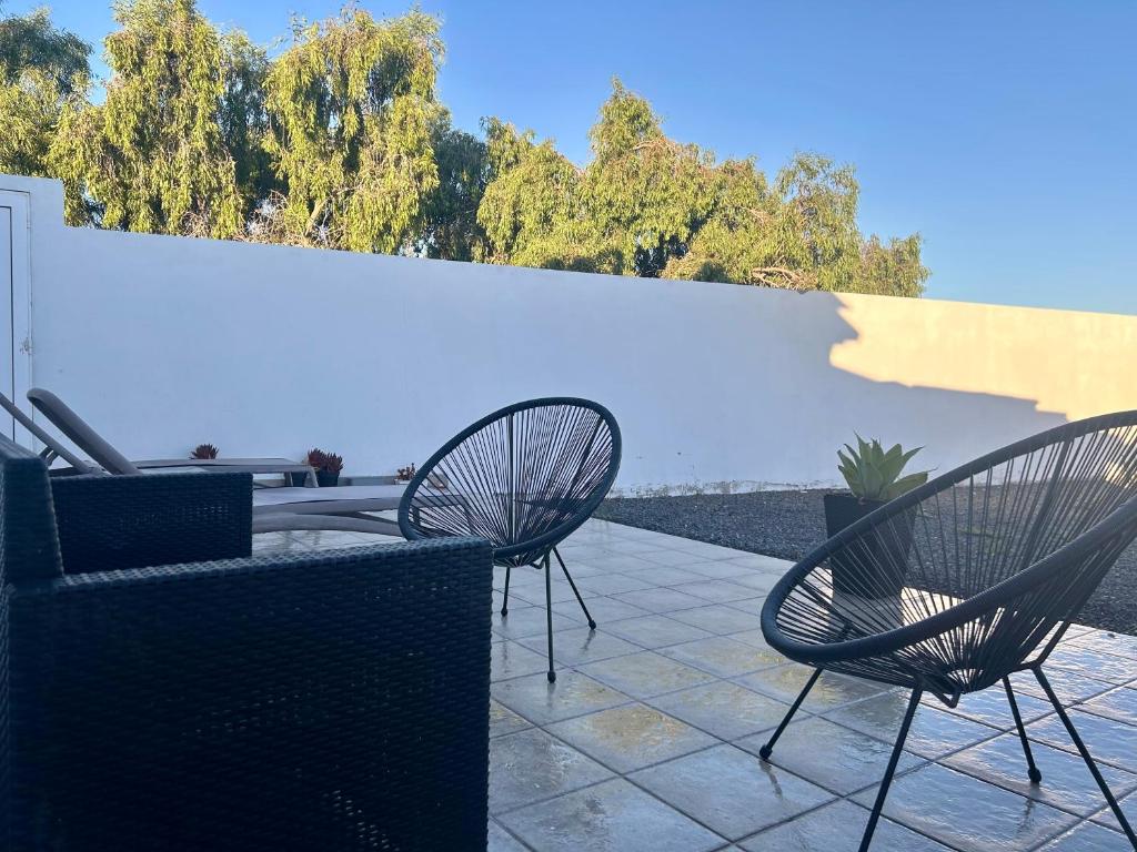 three chairs and a table on a patio with a white wall at VillaMar in Villaverde