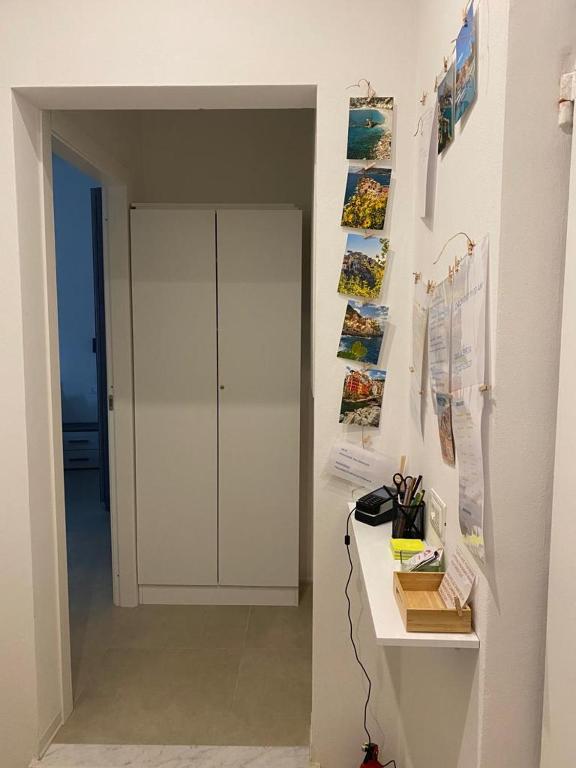a hallway with a desk and a wall with posters at Guesthouse Via San Martino No Elevator in La Spezia