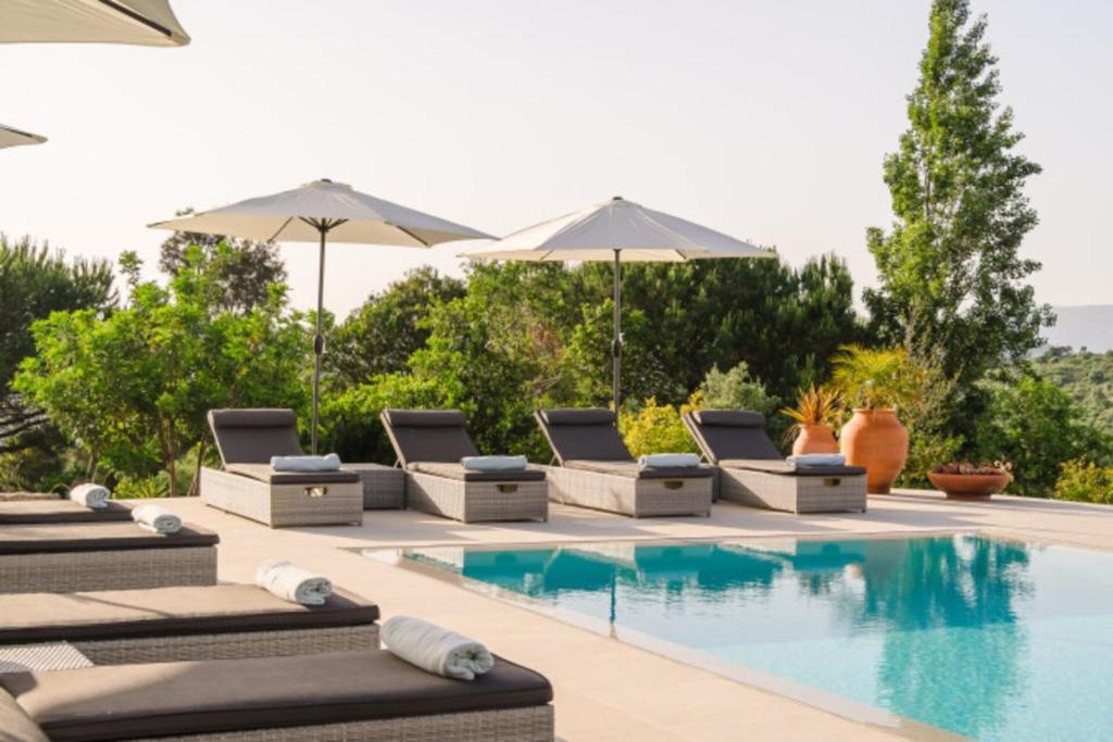 a pool with lounge chairs and umbrellas next to it at Vila das Acácias - Boutique Villa in Wine Country in Alenquer
