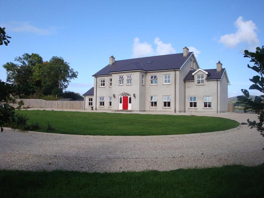 une grande maison blanche avec une porte rouge dans l'établissement Red Gate House B&B, à Malin
