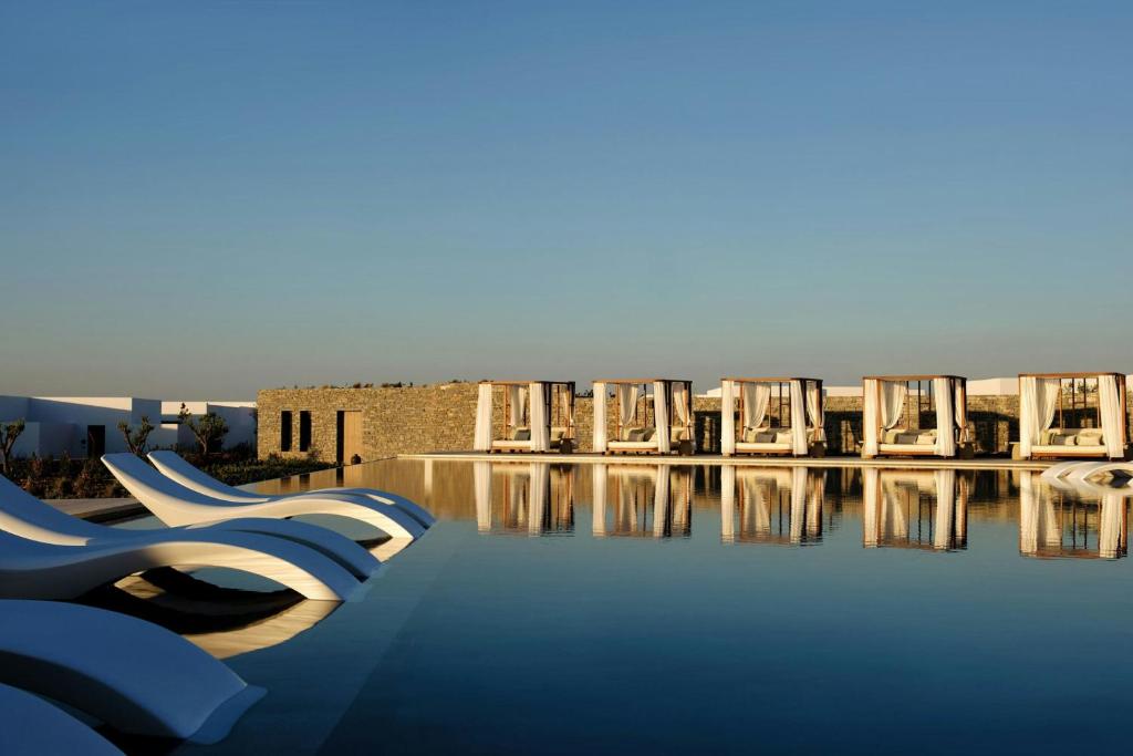 a group of chairs sitting next to a swimming pool at Oroséa Paros - Adults Only, Autograph Collection in Naousa