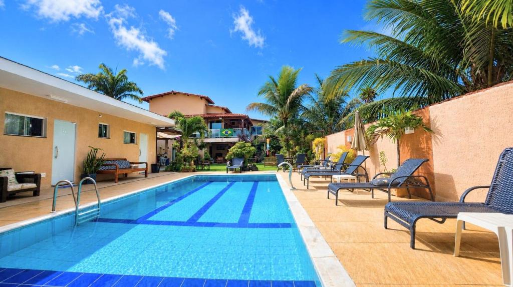 a swimming pool with lounge chairs next to a house at Pousada Recanto do Chef in Búzios