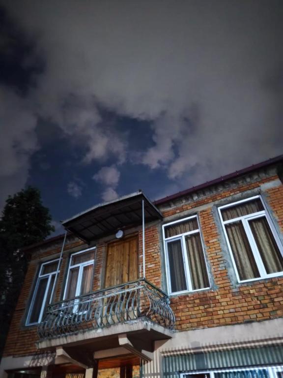 a brick building with a balcony and a cloudy sky at Cozy home in Zugdidi