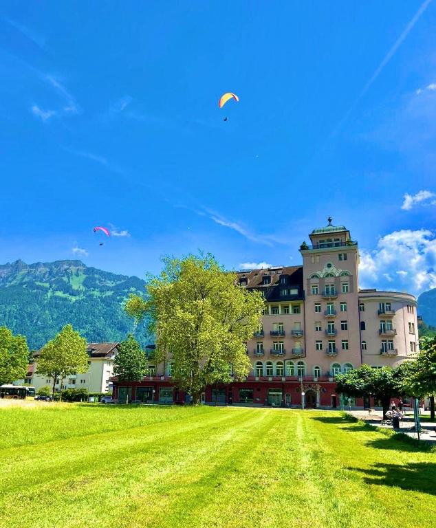 a large building with a grass field in front of it at Apartment by Mario in Interlaken