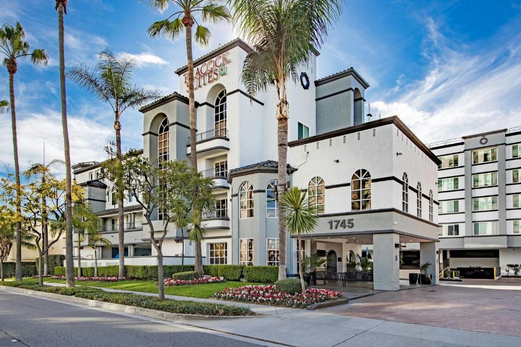 a white building with palm trees in front of it at Peacock Suites in Anaheim