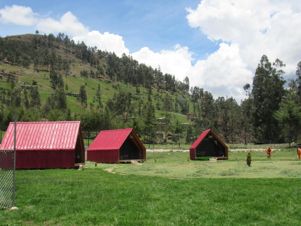 three barns in a field with a mountain in the background at Edén del Aliso in Santa Barbara