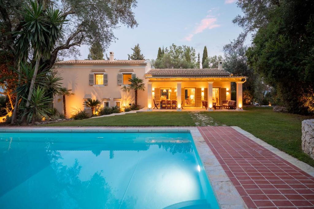 a house with a swimming pool in front of a house at Apelia Estate - Among Ancient Olives, Experience the Quiet Soul of Corfu in Corfu