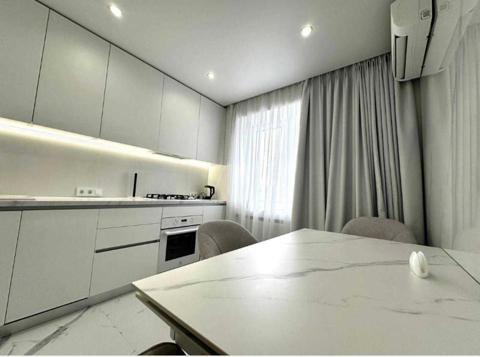 a kitchen with white cabinets and a table and chairs at Білі апартаменти in Dnipro