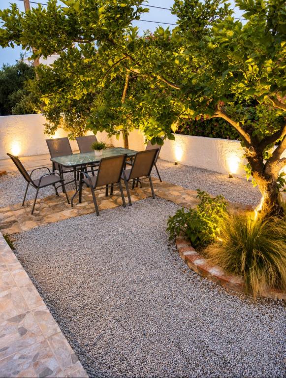 a patio with a table and chairs under a tree at Pipitsa's House-Votsalakia Beach in Votsalákia