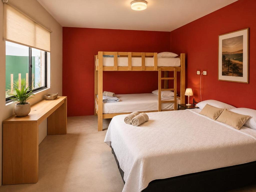 a bedroom with two bunk beds and a red wall at Paracas Desert Lodge&Tours in Paracas
