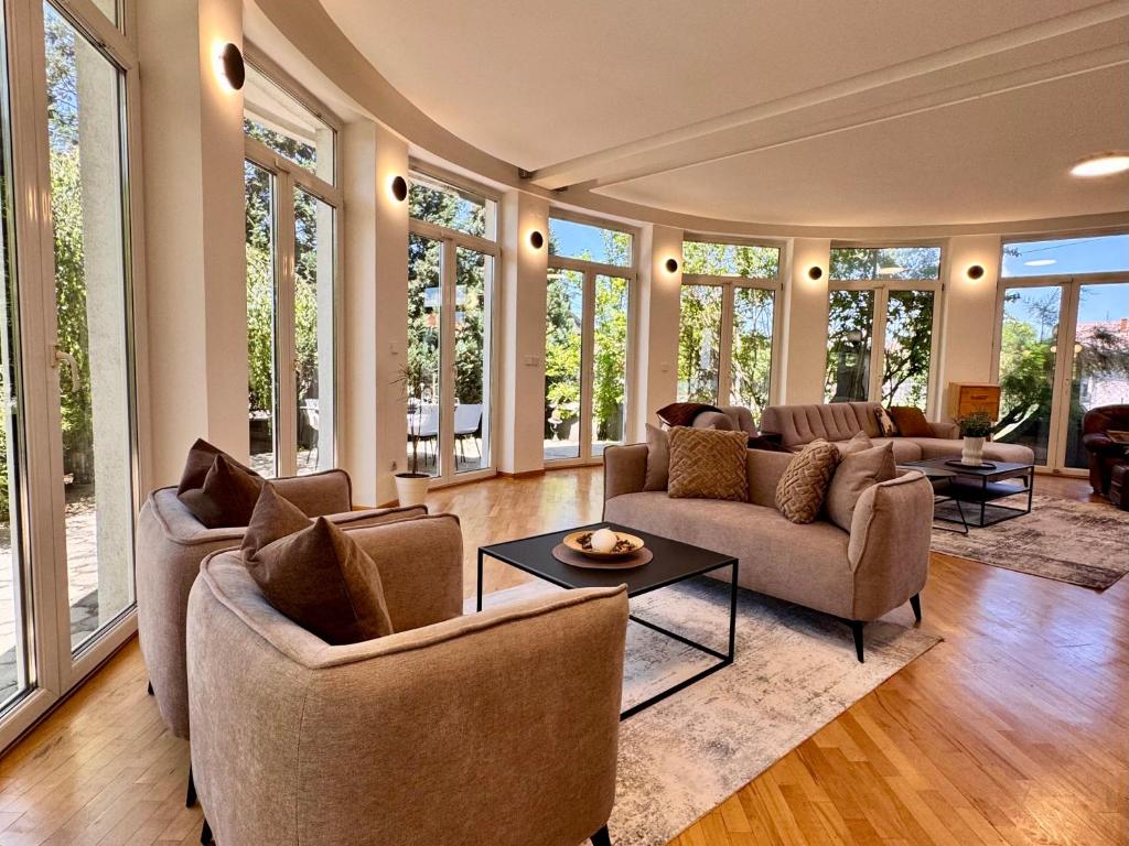 a living room with couches and tables and windows at Royal Sun Villa in Sarajevo