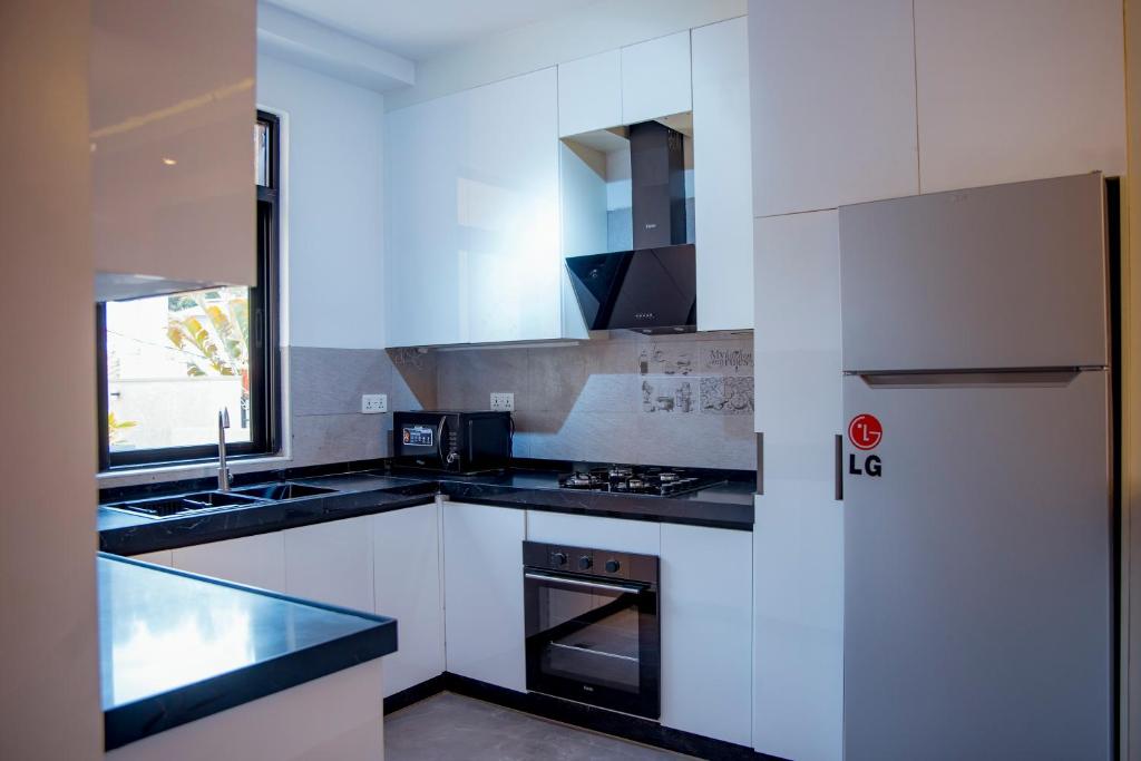 a kitchen with white cabinets and black counter tops at Kiara Apartments in Kigali