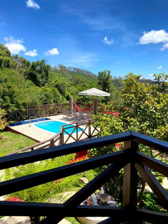 Blick vom Balkon eines Hauses mit Swimmingpool in der Unterkunft Chalés Nascer da Lua in Monte Verde