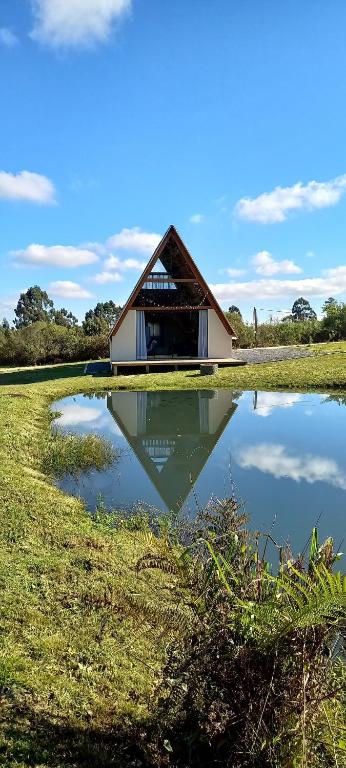 a small house with a reflection in a pond at Chalé Raio de Sol- Colônia Witmarsum in Palmeira