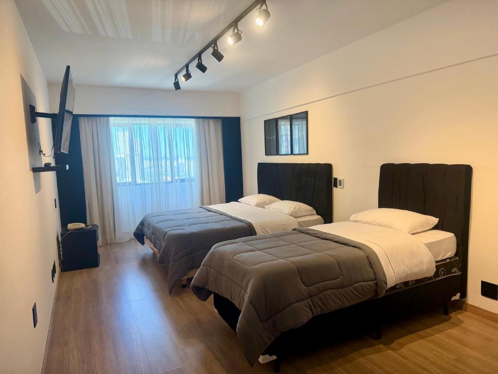 a hotel room with two beds and a window at Hotel Sol Alphaville1505 in Barueri