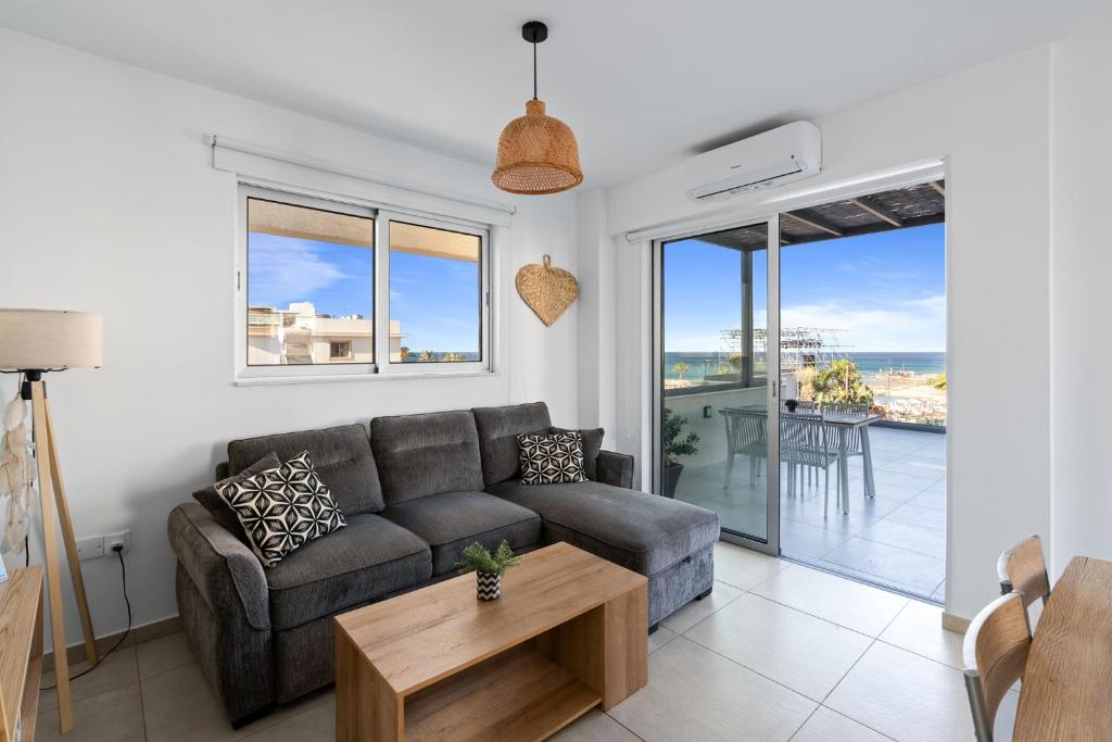 a living room with a couch and a table at WAKE UP BY THE SEA BEACHFRONT FLATS - Protaras in Protaras