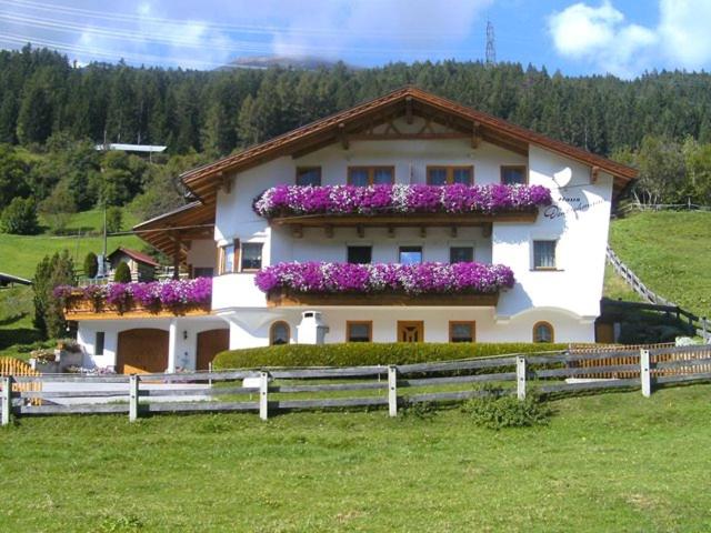 uma casa branca com flores roxas em cima em Haus Deutschmann em Wenns
