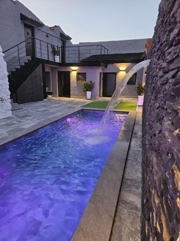 a swimming pool with a waterfall in front of a house at La Casa Los Patios in Mahora
