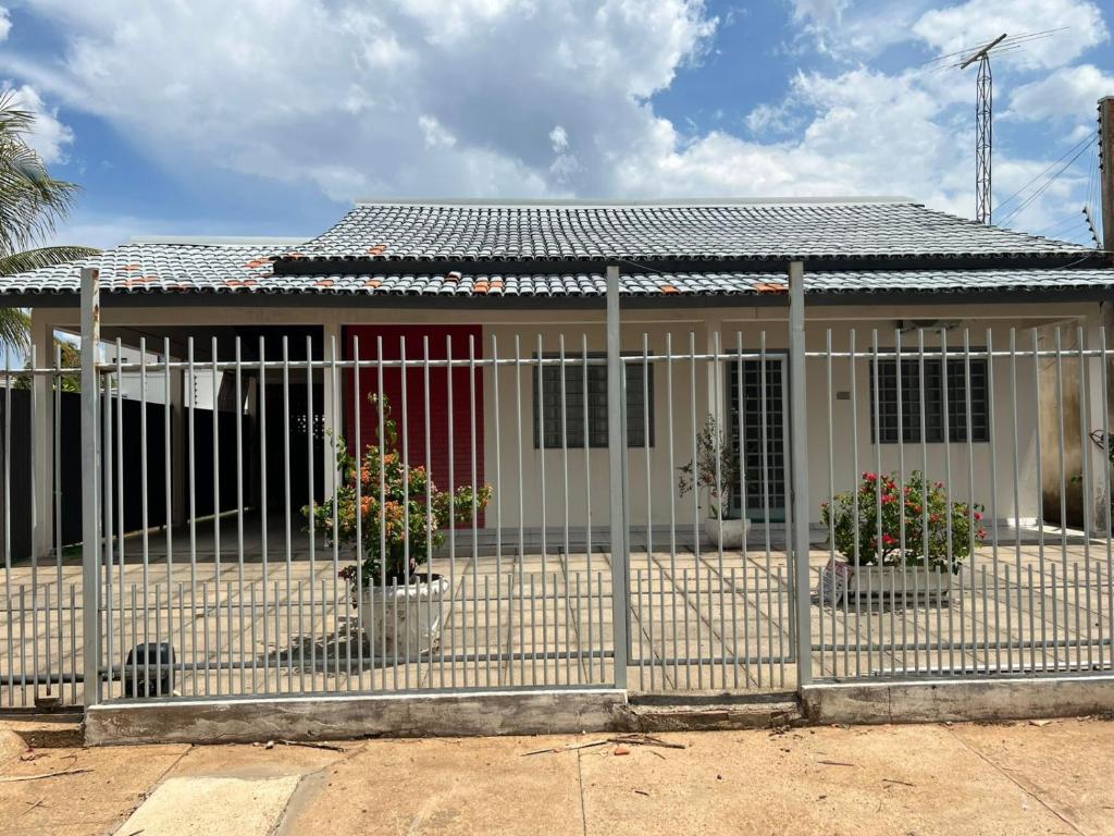 a house with two potted plants in front of a fence at Casa no centro in Primavera do Leste
