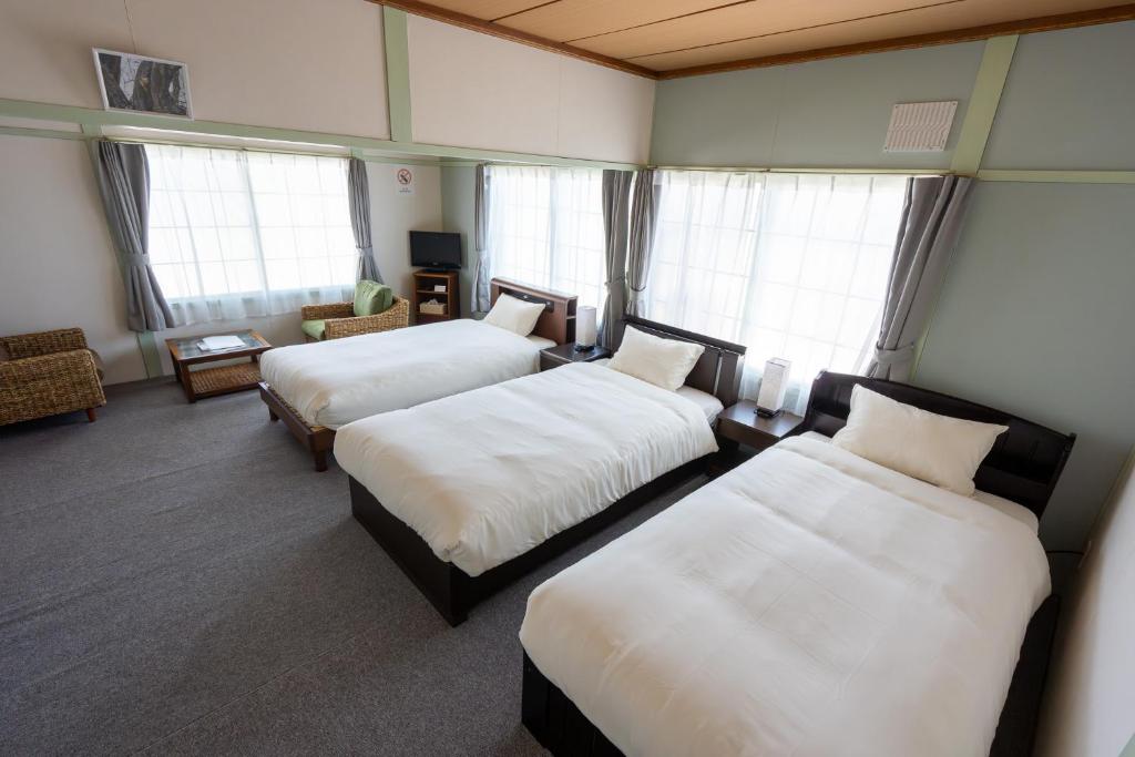a room with two beds and a couch and windows at 暮泊くらはく 1日 1組様限定 5名様まで宿泊可能 in Mikasa