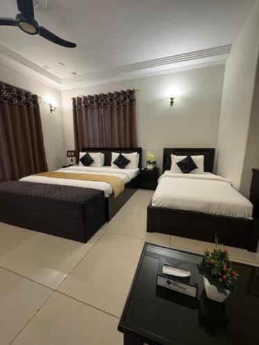 a hotel room with two beds and a table at Hotel Moon Light view in Lahore