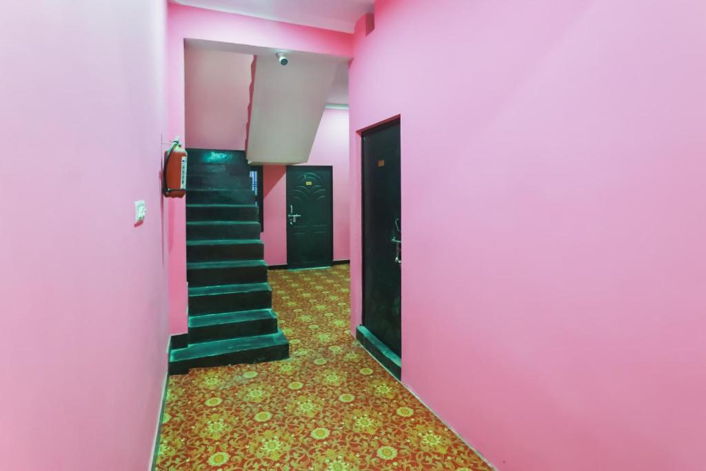 a corridor with pink walls and stairs in a room at Hotel O Rajdhani Hotel in Kākori