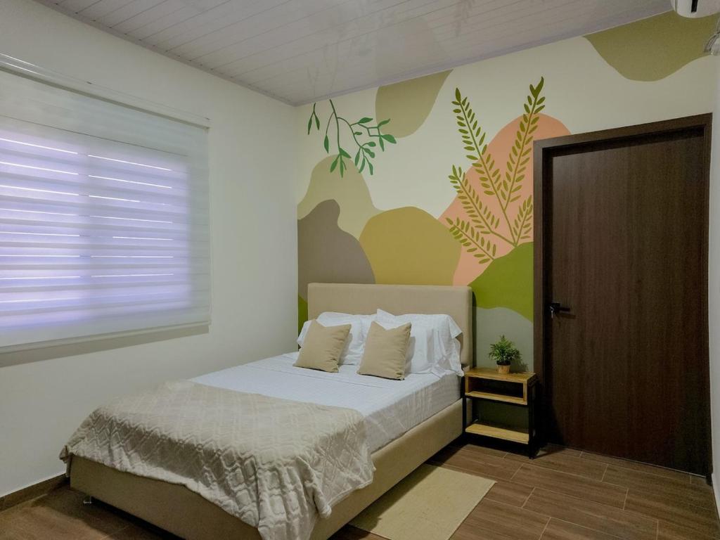 a bedroom with a bed and a wall with plants at Cozy Calm Refuge in Alto Boquete