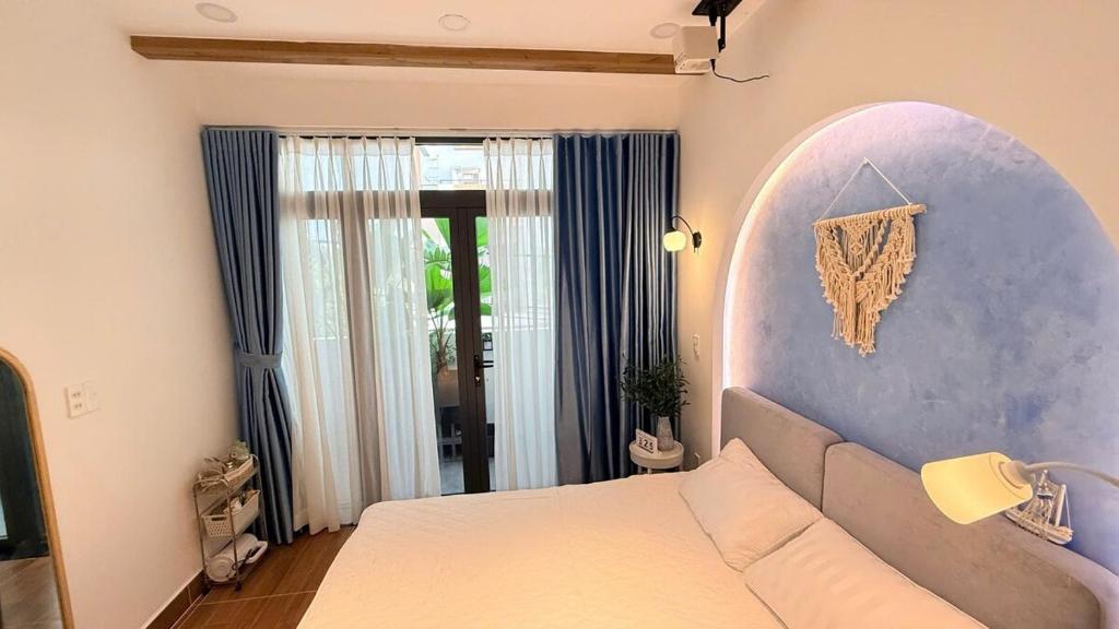 a bedroom with a white bed and a blue wall at LàMin Homestay in Ấp Long Ðại