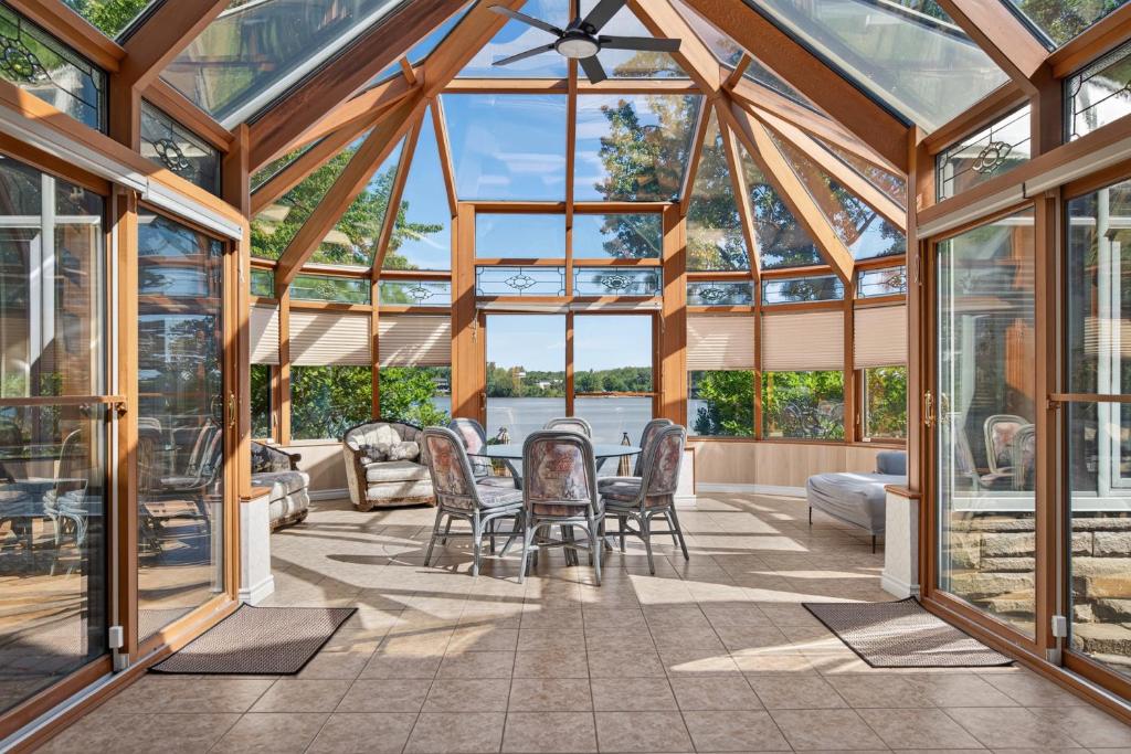 a conservatory with glass walls and tables and chairs at Private Waterfront Villa 9 BR Peaceful in Laval