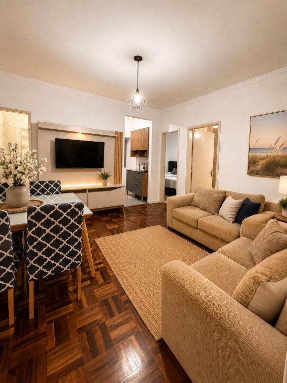 a living room with a couch and a table and a tv at Roupa cama Wi-Fi garagem ar Cond beira mar 50 m in Tramandaí