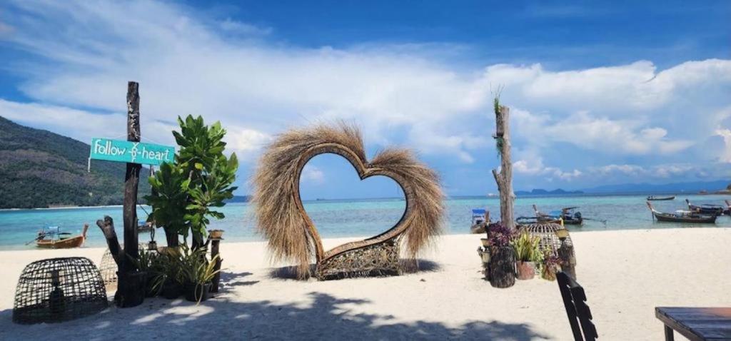 a beach with a heart shaped bench on the sand at Lipe Beach Resort in Ko Lipe