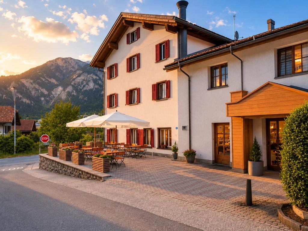 ein Gebäude mit Tischen und Sonnenschirmen davor in der Unterkunft Alpine Hotel Reich in Cazis