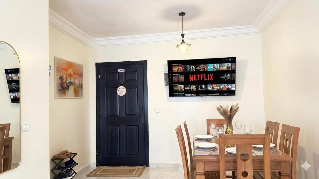a dining room with a table and a black door at Cozy Apartment Near Rabat & Beach in Temara