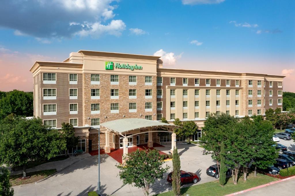 a hotel building with a parking lot in front of it at Holiday Inn Garland by IHG in Garland